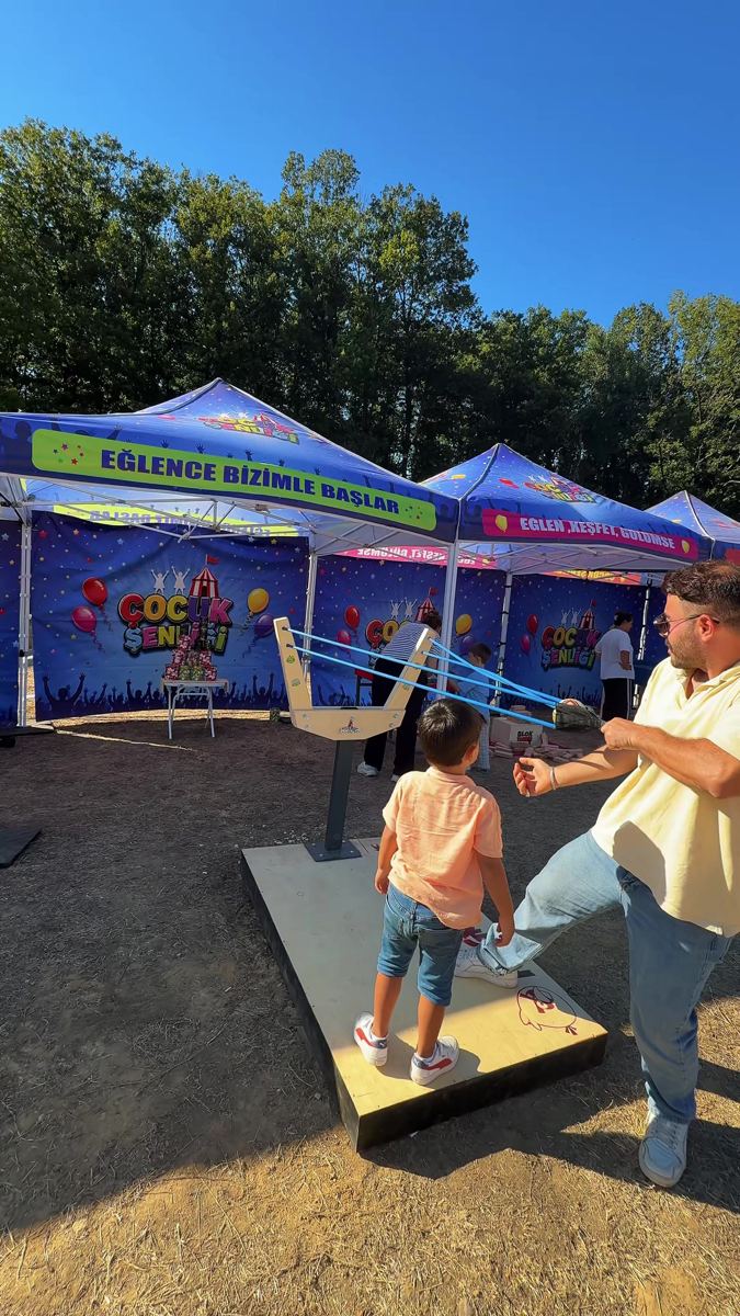 Festival alanında sapan ve hedef oyununu babasıyla oynayan çocuk