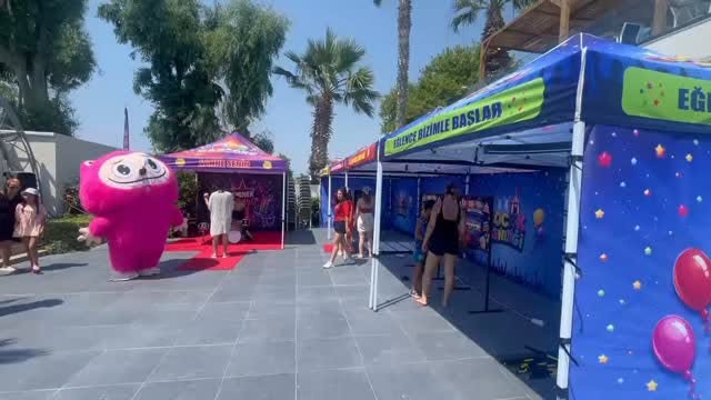 Festival alanında kurulmuş renkli oyun çadırları ve maskot karakter